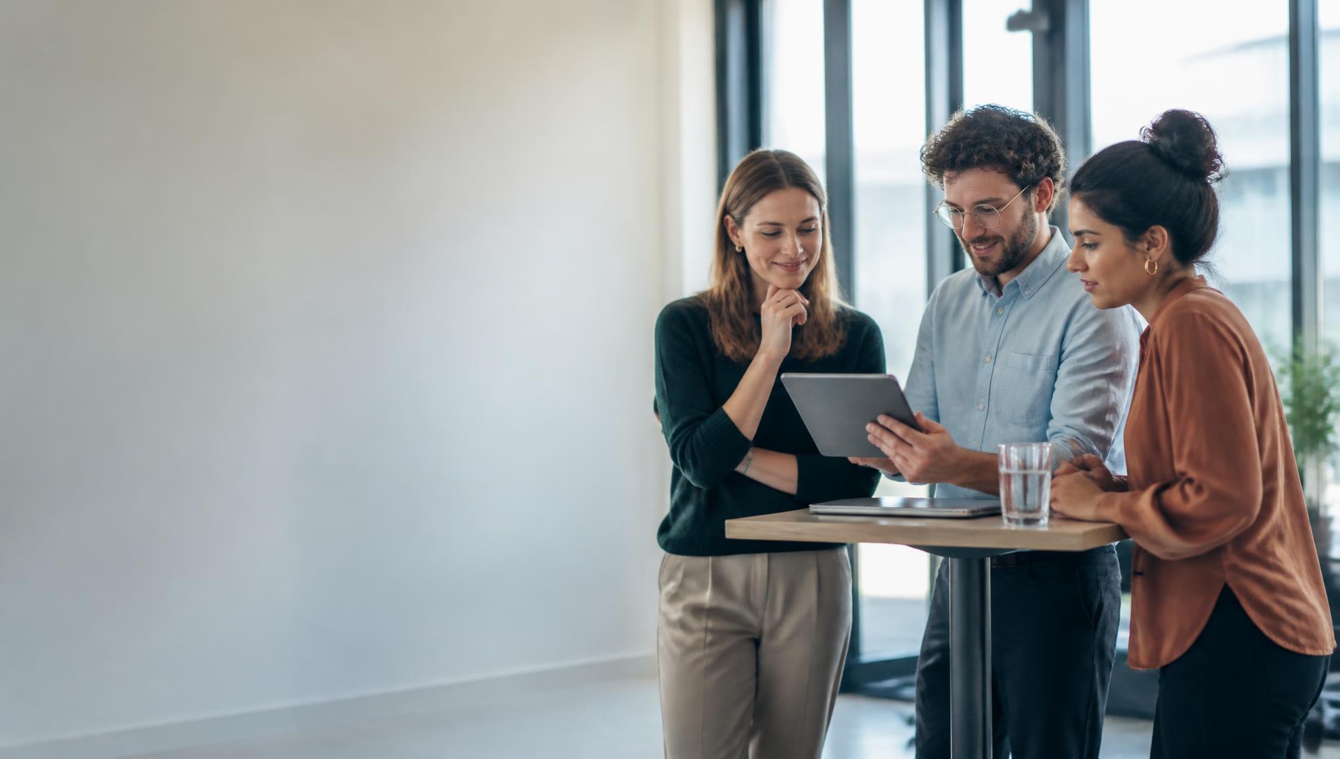 Three colleagues reviewing a health report together on a tablet in a bright office